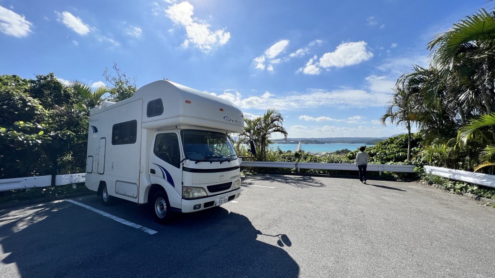 青空と海を望む場所に停車したキャンピングカー